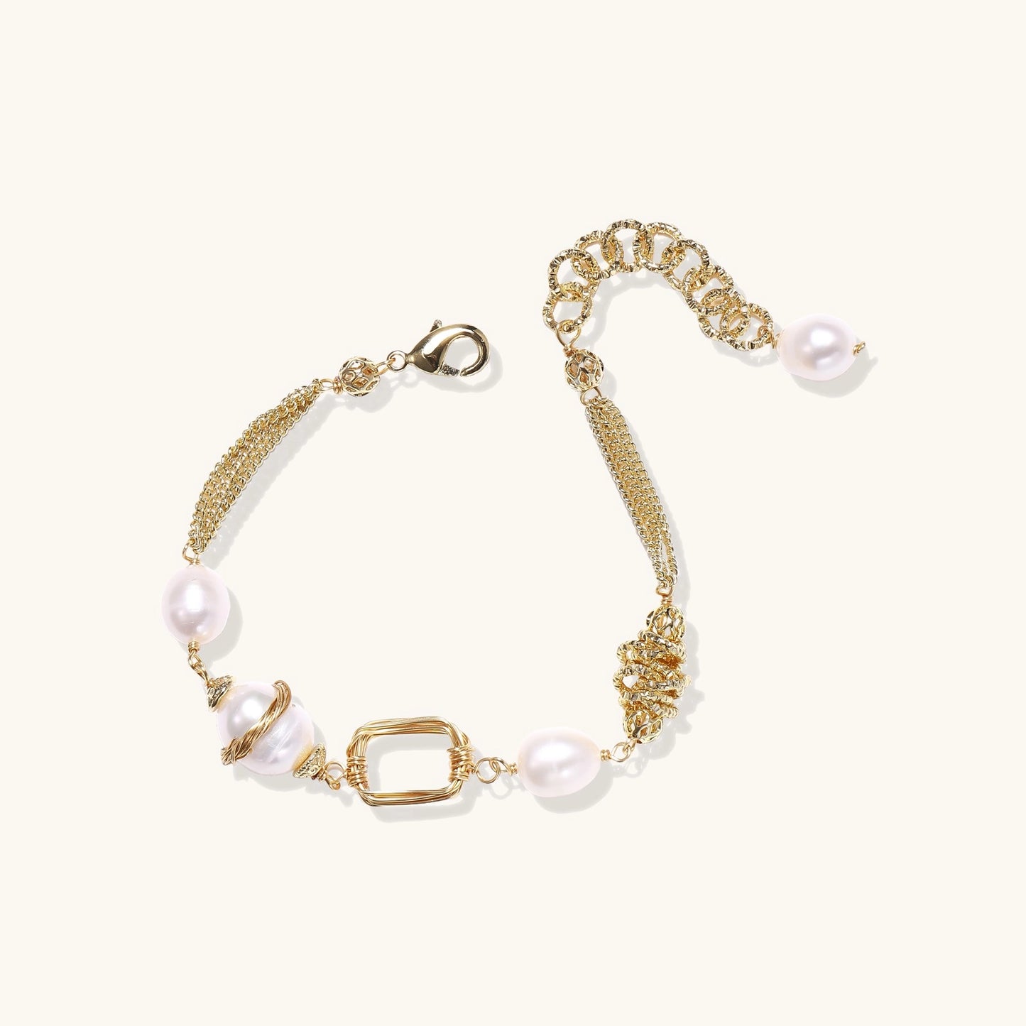 Gold-plated bracelet featuring cream freshwater pearls and decorative chain links on white background.