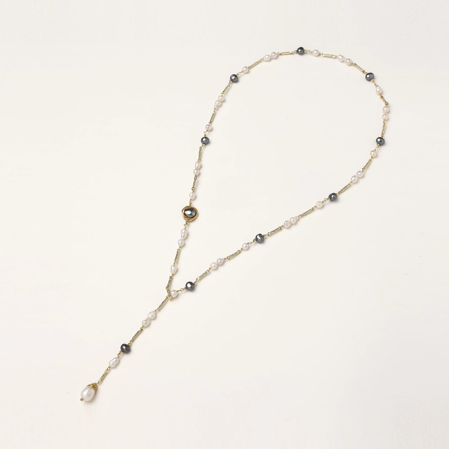 Long gold-plated necklace with alternating white and gray freshwater pearls spaced along delicate chain segments