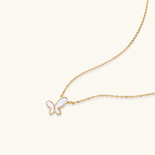 Delicate gold butterfly necklace with white mother of pearl wings on fine chain, displayed on neutral background.
