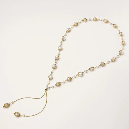 Adjustable gold lariat necklace with freshwater pearls nested in delicate cage settings and Y-shaped tassel drop