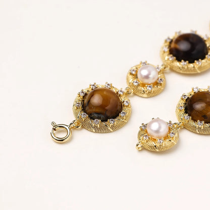 Ornate gold-plated bracelet with alternating brown tiger's eye stones and white freshwater pearls in crystal-accented settings