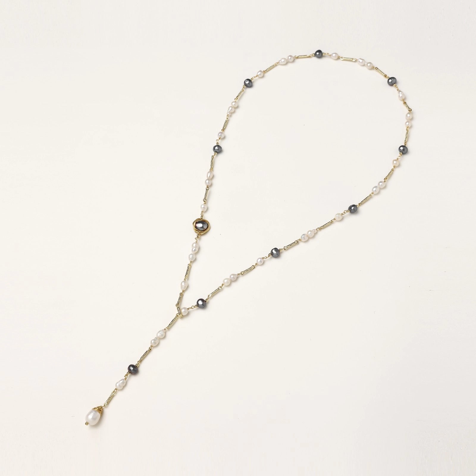 Long gold-plated necklace with alternating white and gray freshwater pearls spaced along delicate chain segments