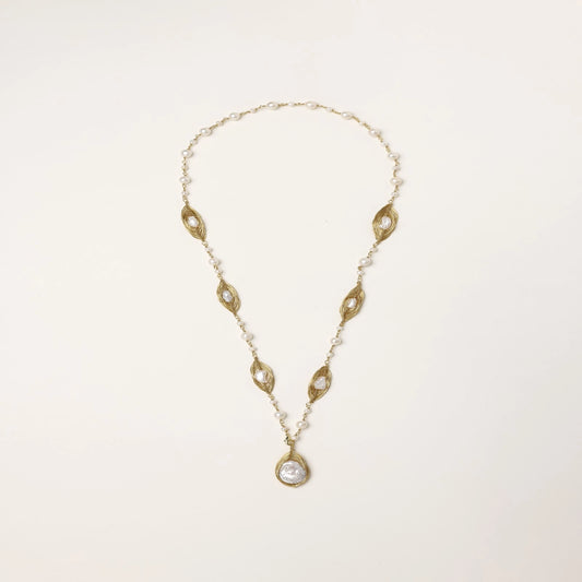 Long gold-plated necklace with eye-shaped elements, freshwater pearls, and baroque pearl pendant on neutral background.