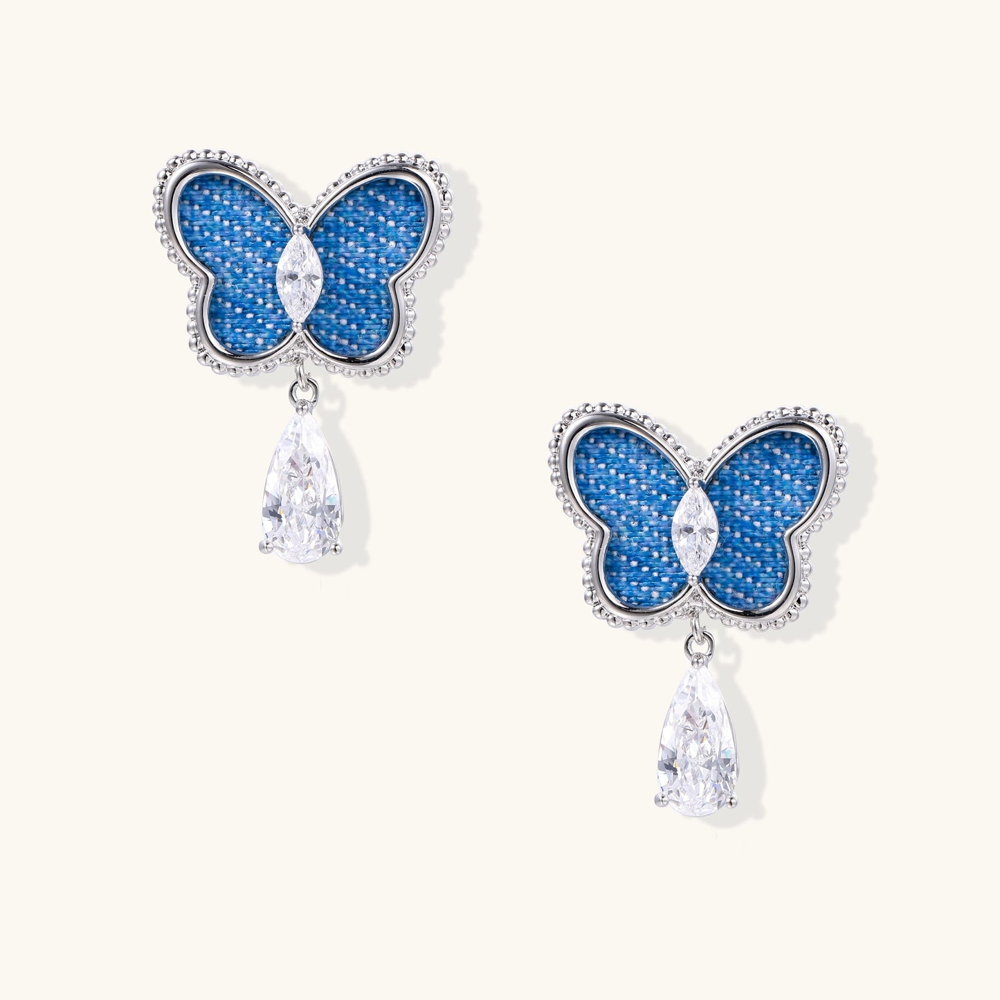 Silver-toned butterfly earrings with blue enamel wings and crystal drop pendants on white background.