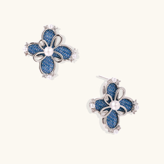 Blue denim flower stud earrings with silver framework, white pearl centers, and crystal accents on cream background.