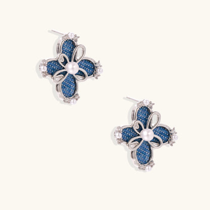 Blue denim flower stud earrings with silver framework, white pearl centers, and crystal accents on cream background.