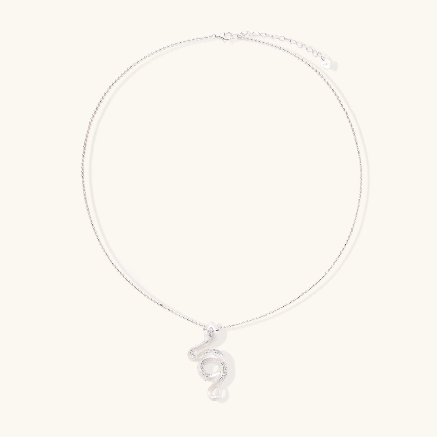 Sterling silver snake pendant necklace with zirconia crystals on adjustable chain against cream background