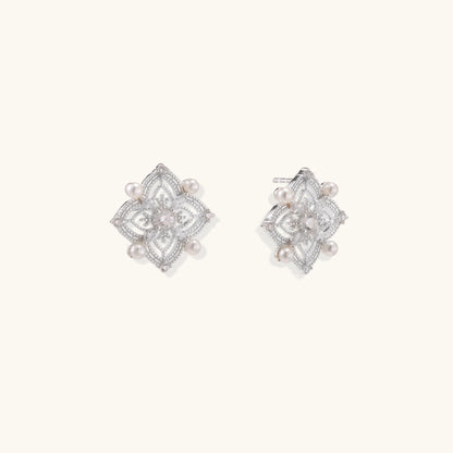 Detailed view of sterling silver stud earrings with geometric filigree design and small freshwater pearls on white background.
