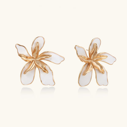 Large floral stud earrings with gold-plated brass petals and white enamel centers on neutral background