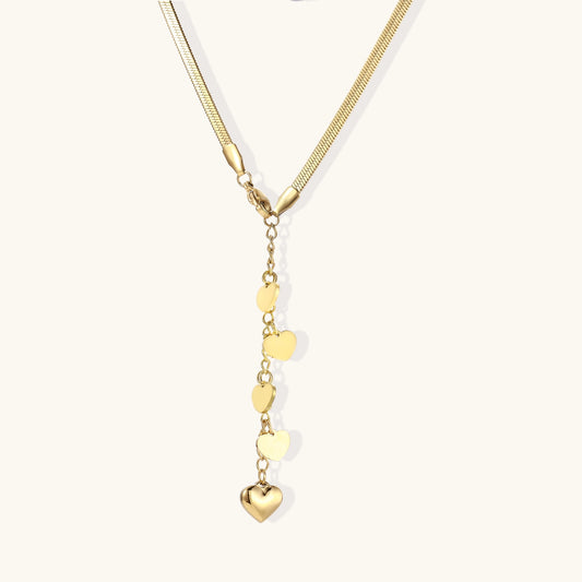 Gold-plated necklace with cascading heart charms in graduated sizes on herringbone chain against white background.