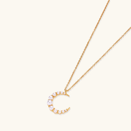 Delicate 18K gold plated necklace featuring crescent moon pendant with white shell pearl beads on neutral background.