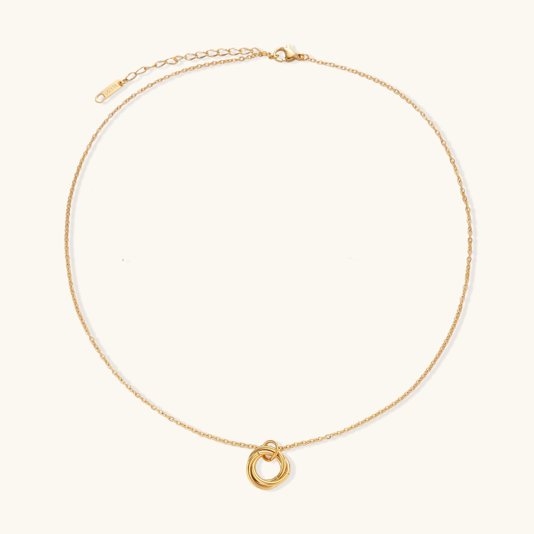 Close-up of a gold-plated stainless steel necklace with interlocking twisted ring pendant on white background