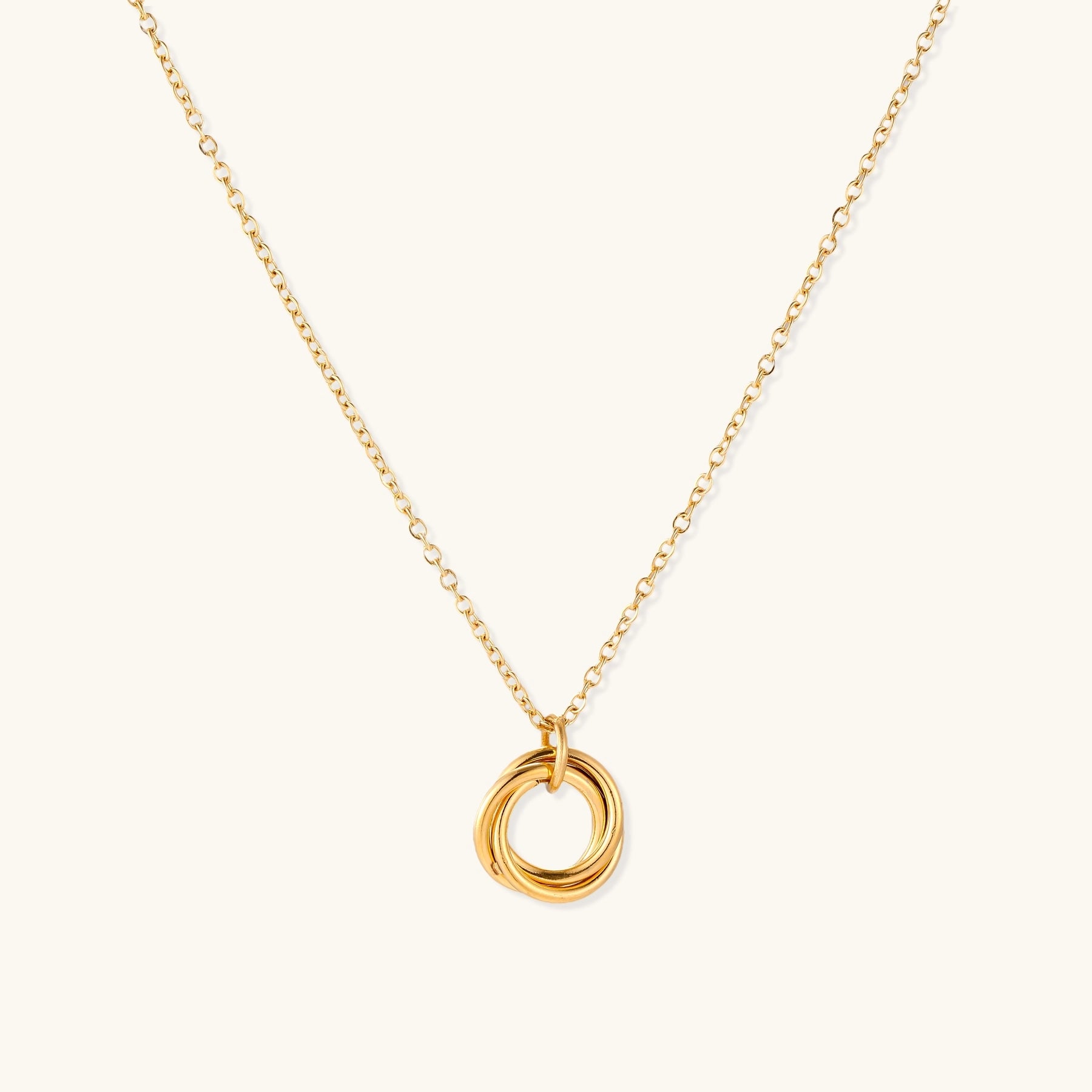 Close-up of a gold-plated stainless steel necklace with interlocking twisted ring pendant on white background