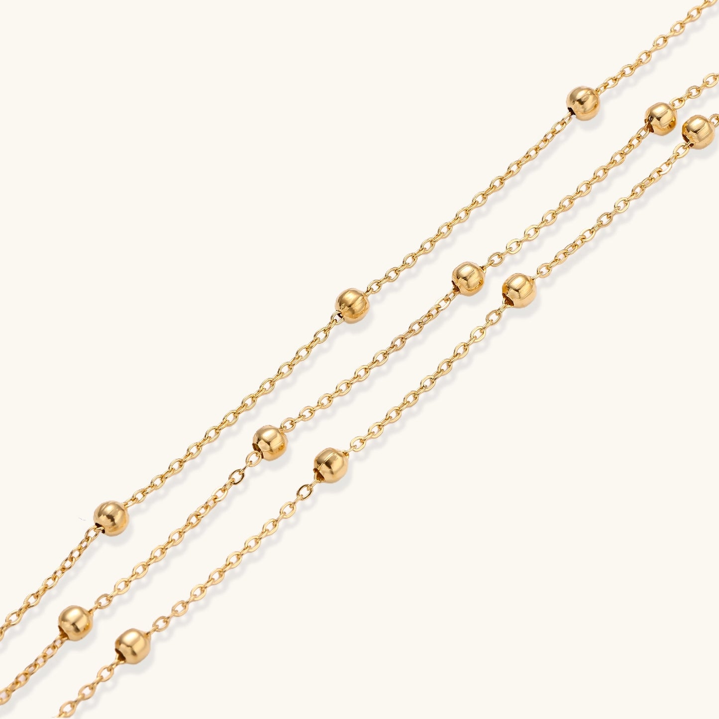 Delicate 18K gold plated bracelet with spherical beads on layered chains and adjustable extender on white background