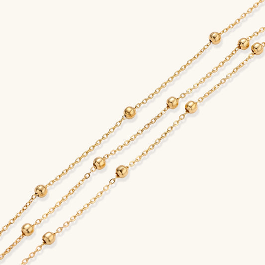 Delicate 18K gold plated bracelet with spherical beads on layered chains and adjustable extender on white background