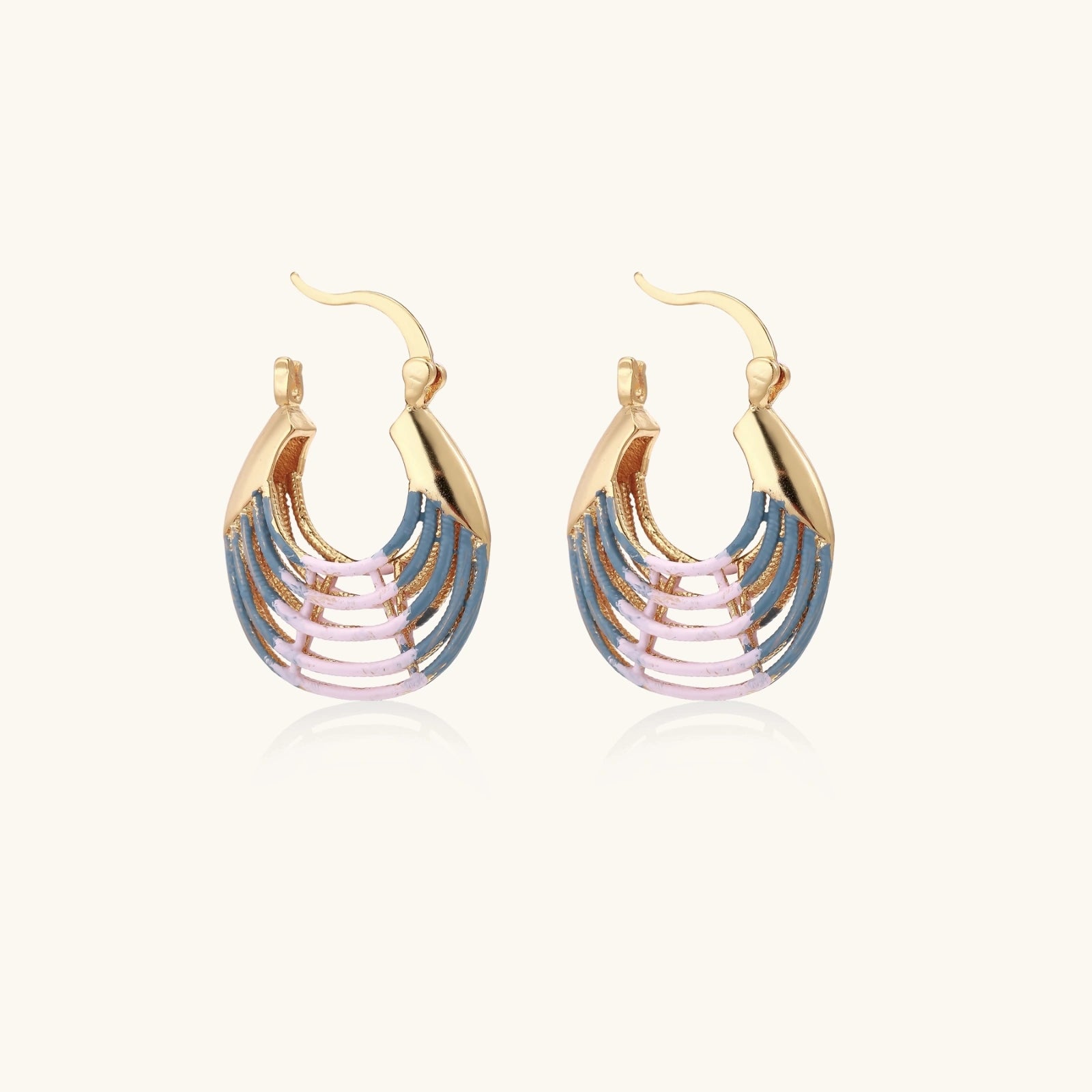 Gold hoop earrings with gradient blue-to-pink enamel in ribbed fan design on beige background