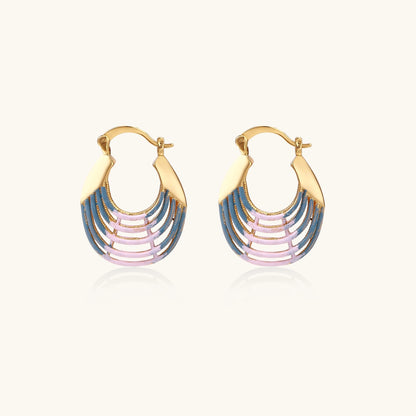 Gold hoop earrings with gradient blue-to-pink enamel in ribbed fan design on beige background