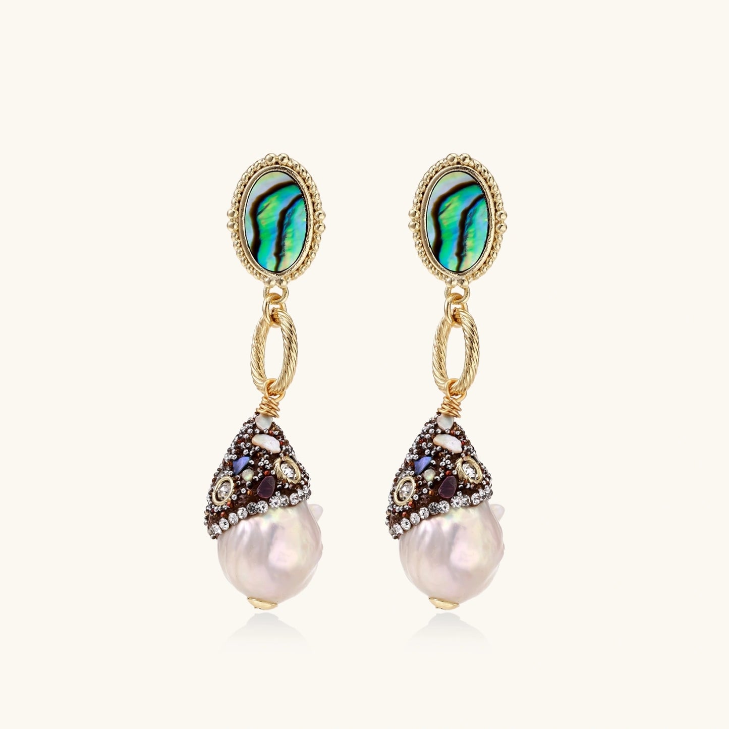 Gold drop earrings with iridescent abalone studs, rope links, jeweled caps and white baroque pearls on cream background