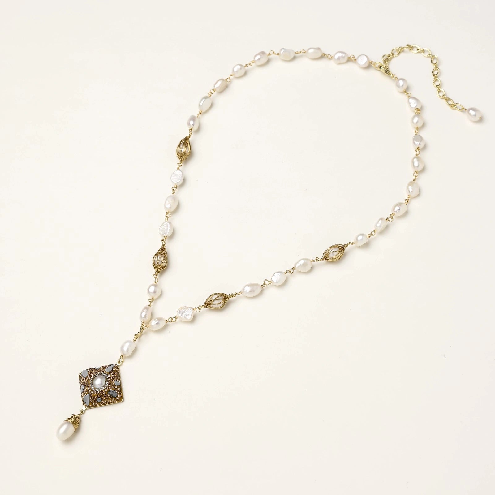 Y-shaped necklace with freshwater pearls, gold filigree stations, and ornate diamond-shaped centerpiece with pearl drop