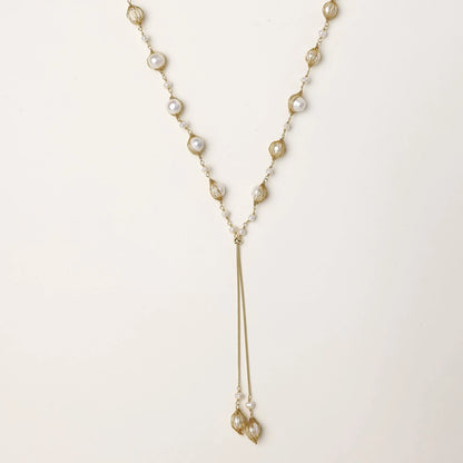 Adjustable gold lariat necklace with freshwater pearls nested in delicate cage settings and Y-shaped tassel drop