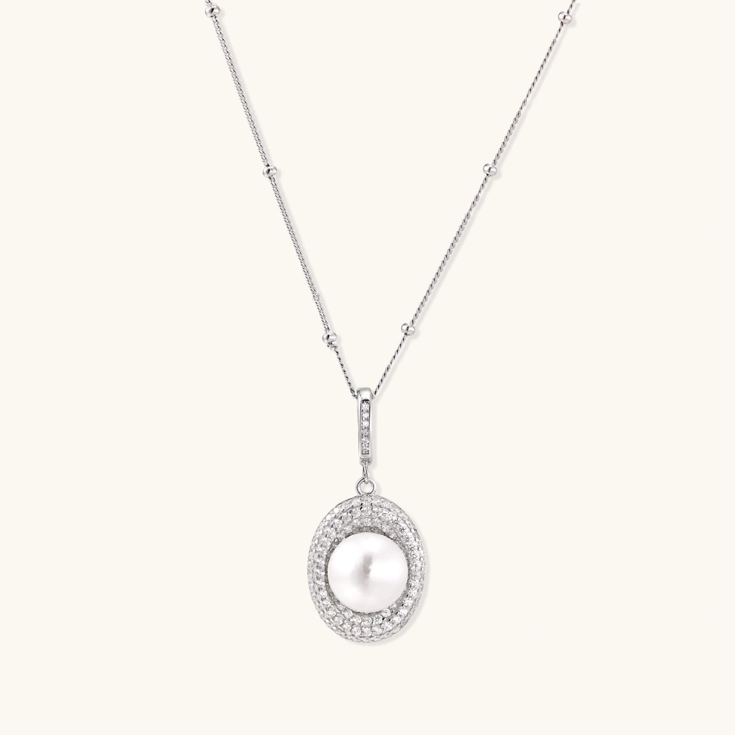 Oval sterling silver pendant with crystal halo surrounding a white freshwater pearl on delicate chain