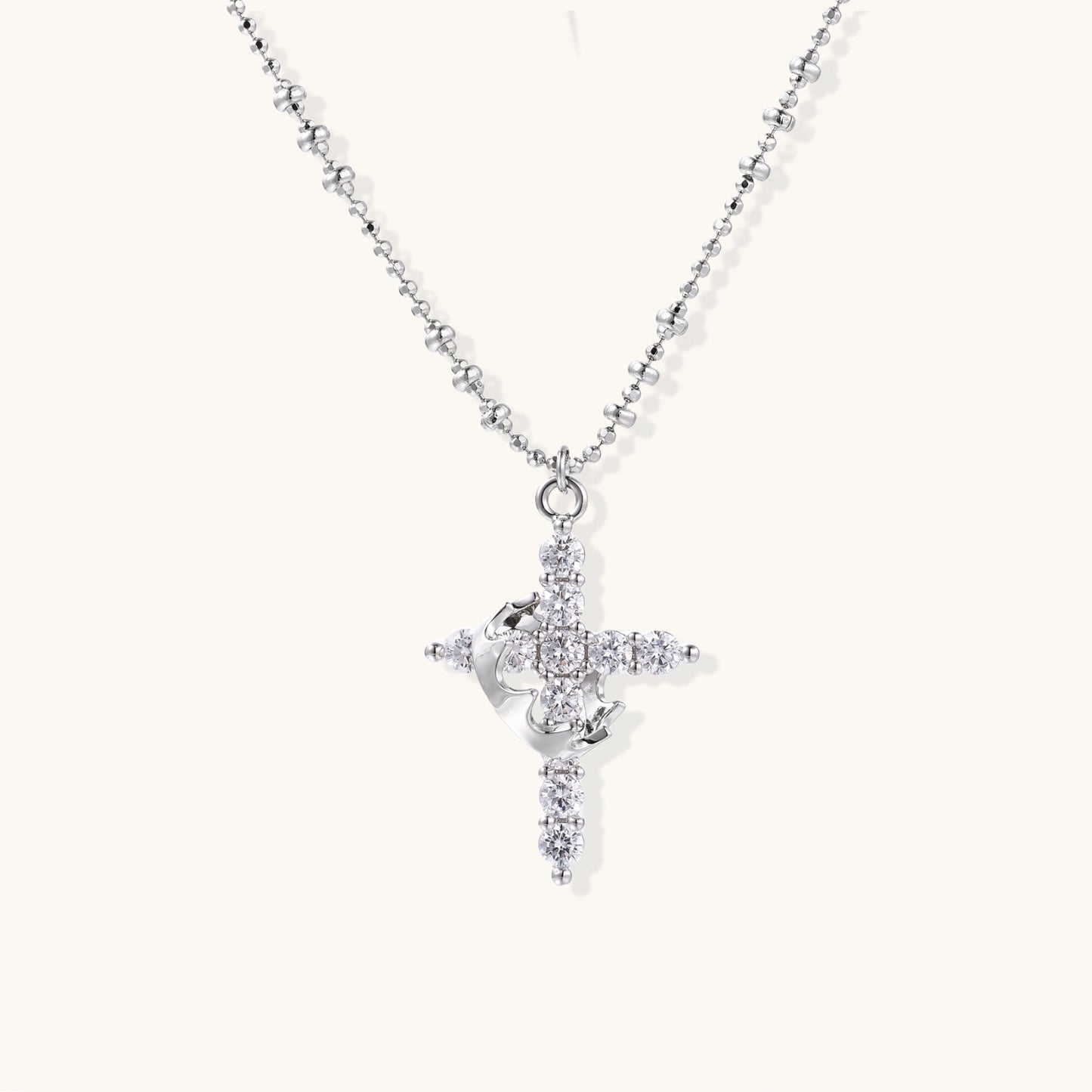 White gold-plated cross pendant adorned with sparkling zirconia stones and crescent moon accent on ball chain