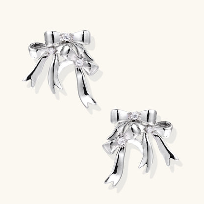 Sculptural bow earrings in polished white gold plate with sparkling zirconia stones and flowing ribbon details