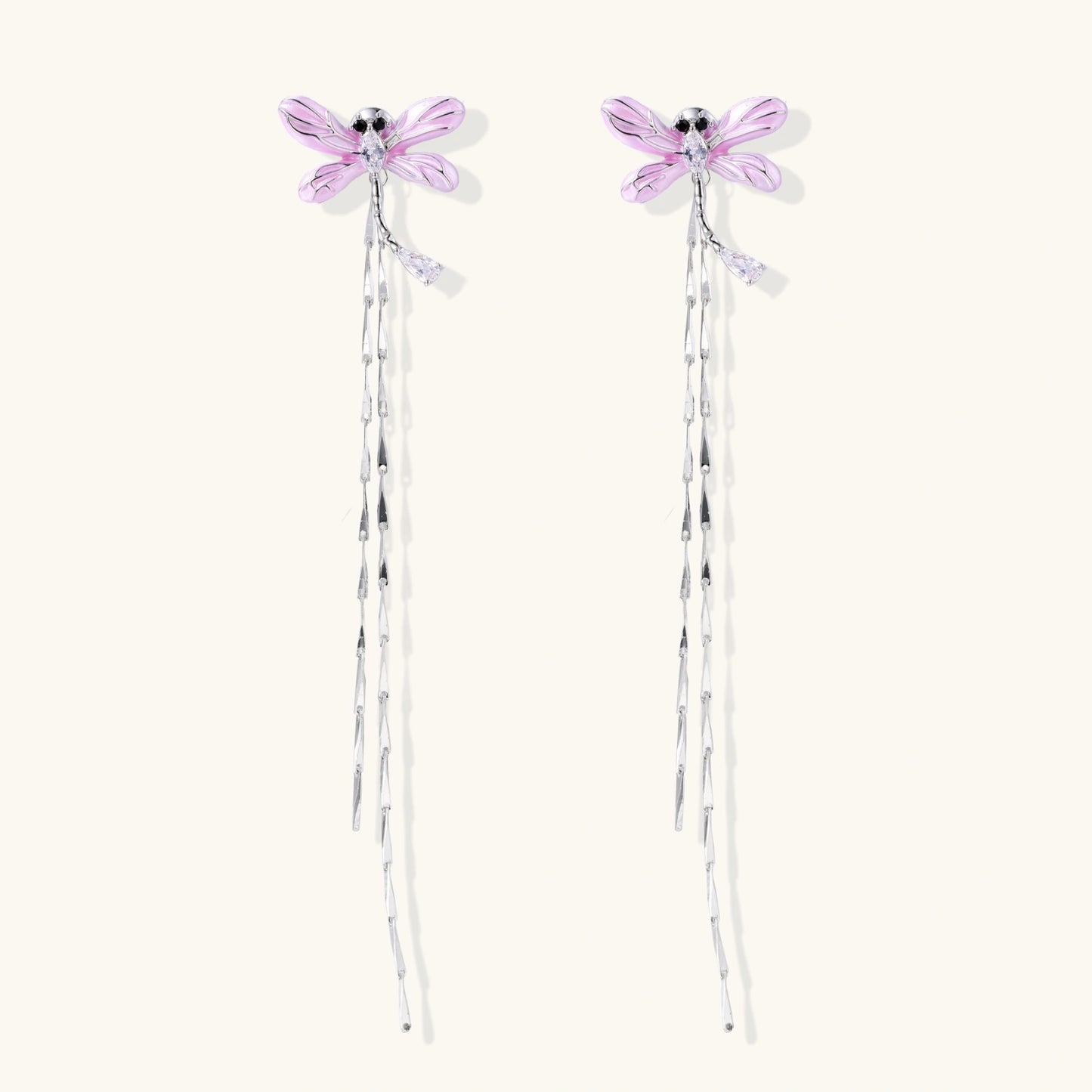 Long drop earrings with translucent lavender enamel dragonfly wings and white gold plated segmented bodies on white background