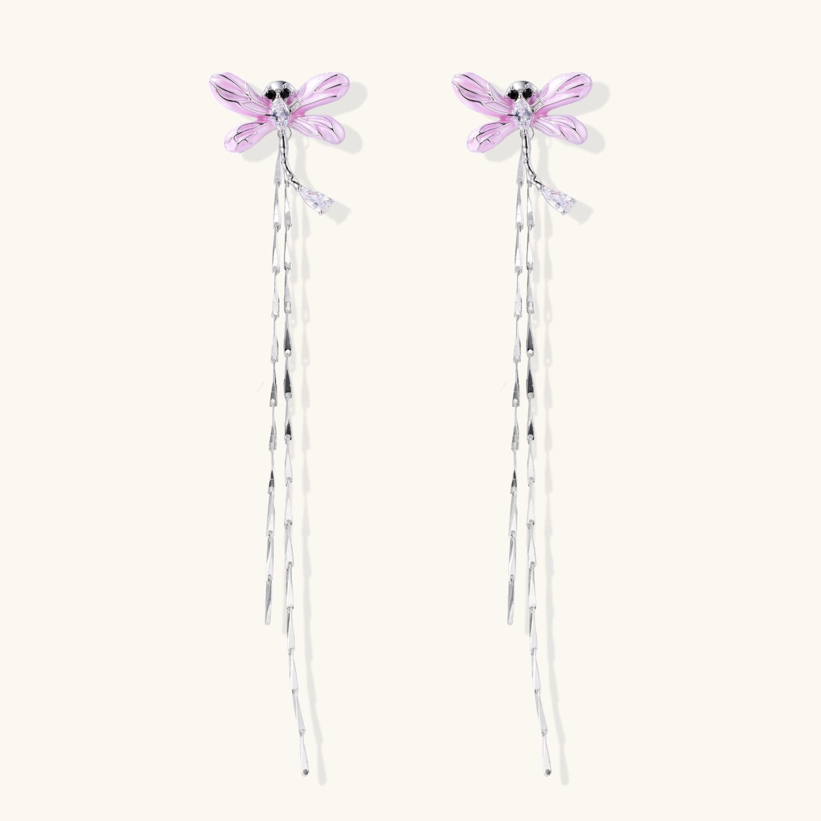 Long drop earrings with translucent lavender enamel dragonfly wings and white gold plated segmented bodies on white background