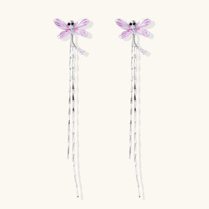 Long drop earrings with translucent lavender enamel dragonfly wings and white gold plated segmented bodies on white background
