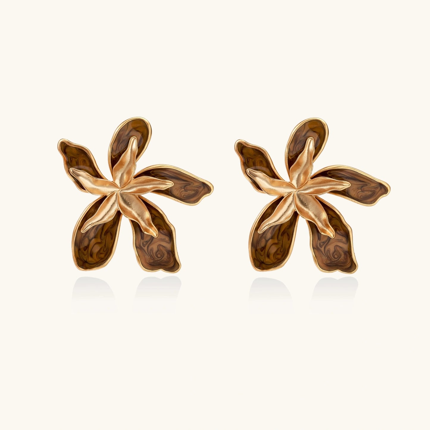 Gold-plated brass flower earrings with brown tortoiseshell enamel petals on cream background
