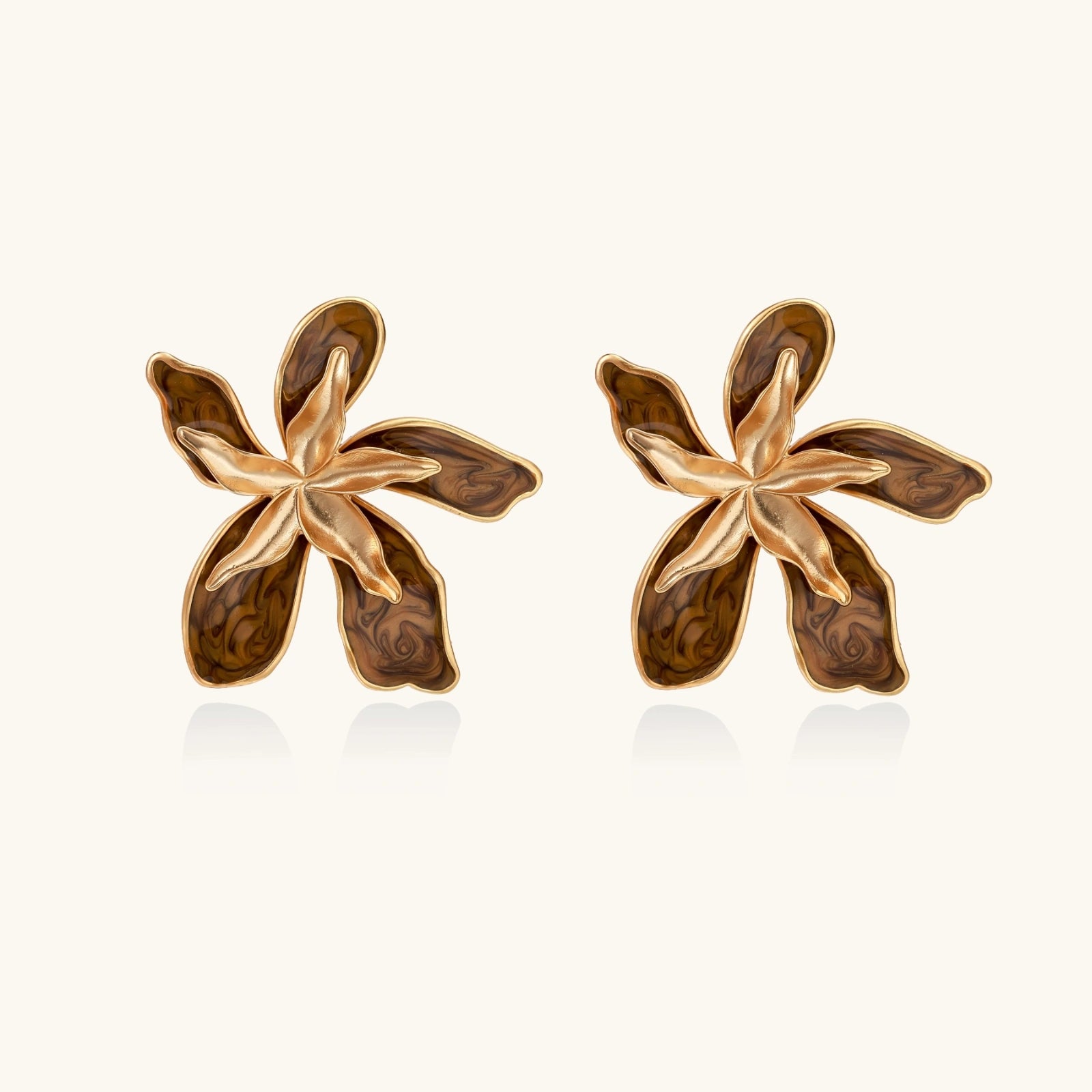 Gold-plated brass flower earrings with brown tortoiseshell enamel petals on cream background