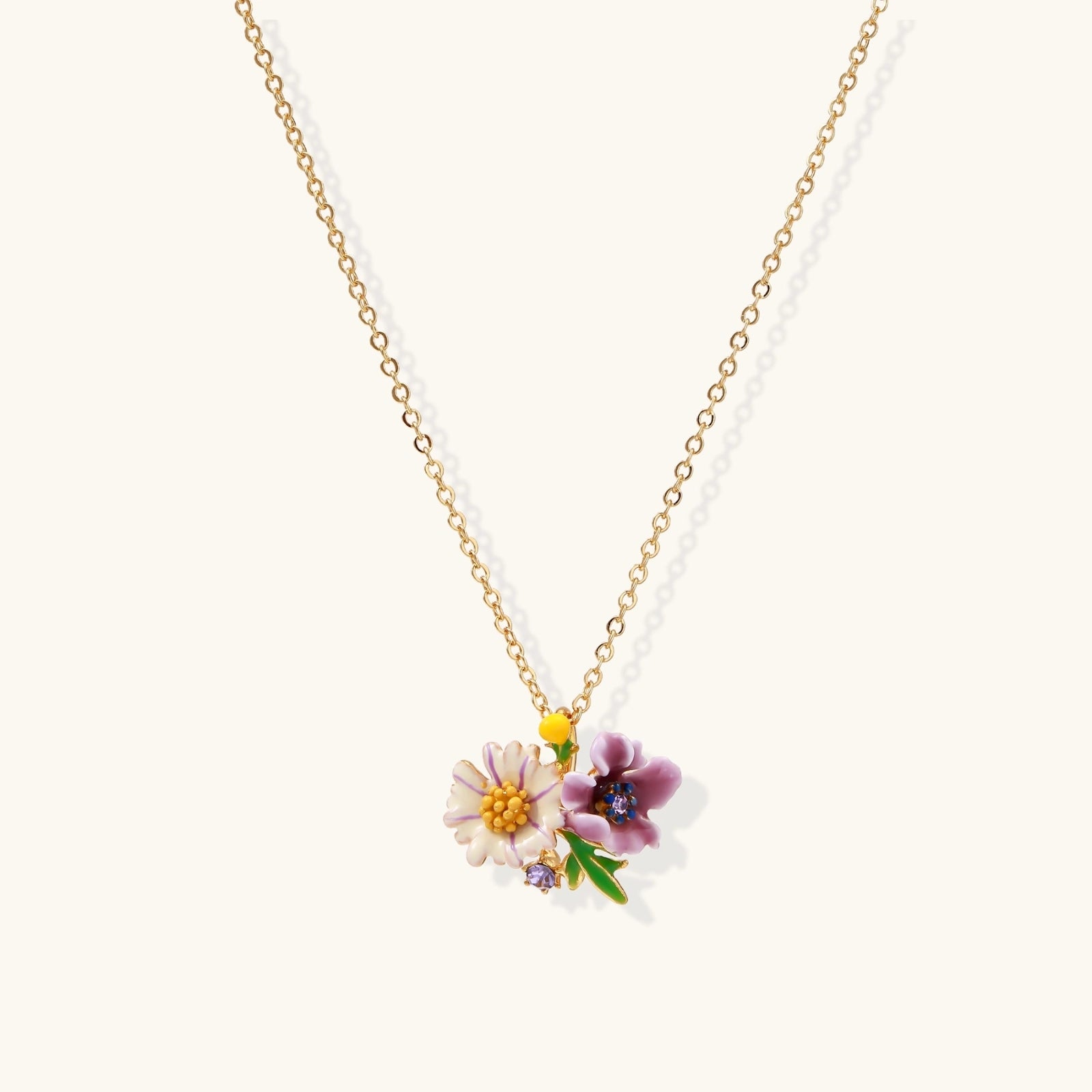 Gold-plated necklace with pink and purple enamel flower pendant featuring crystal accents on cream background
