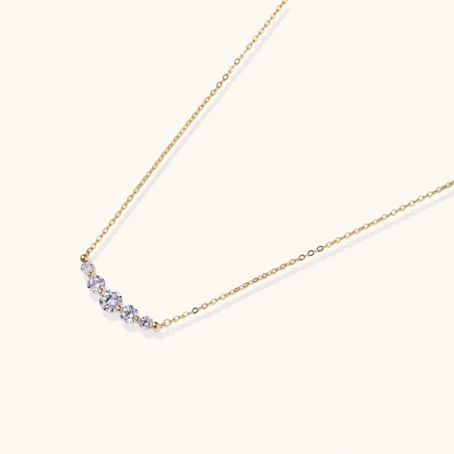 Delicate 14K gold-plated necklace with five graduated zirconia stones arranged in a curved arc on fine chain