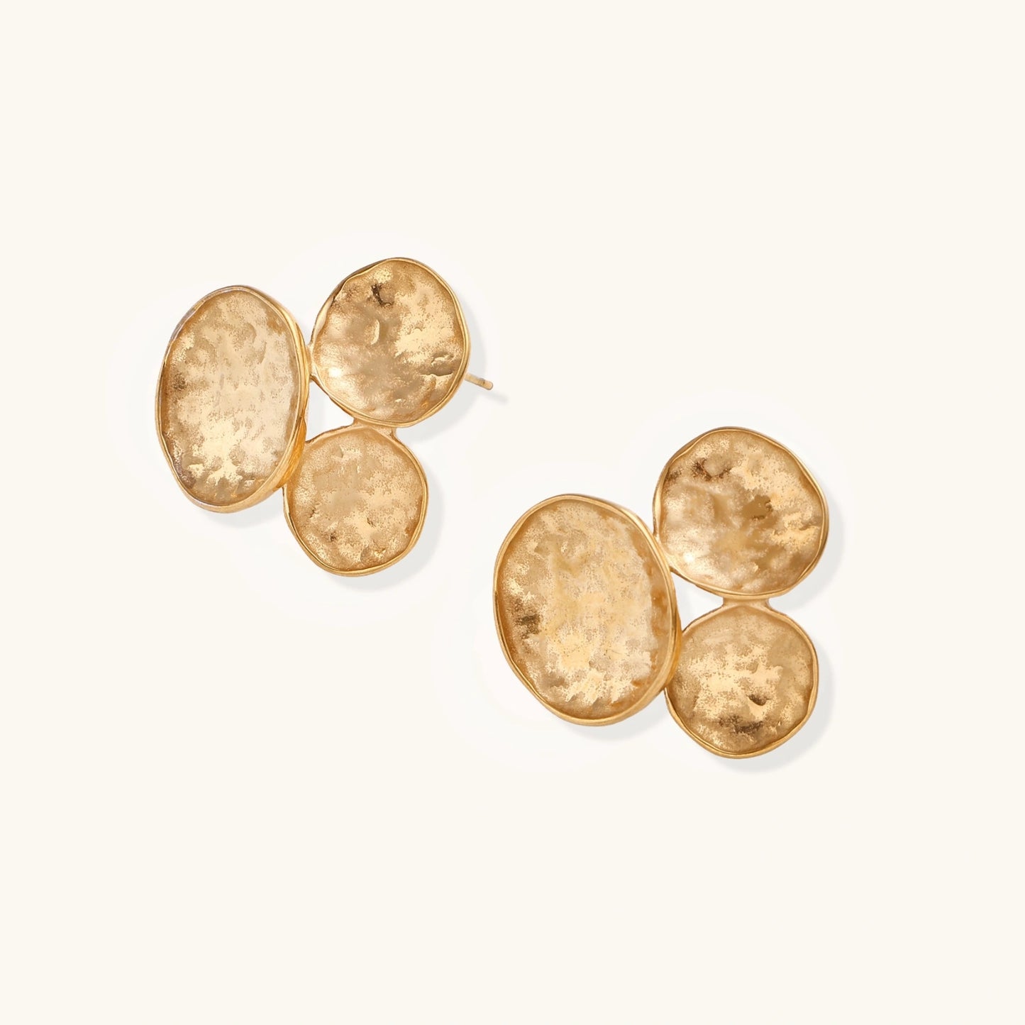 Three hammered gold discs clustered together forming organic statement earrings with textured surfaces