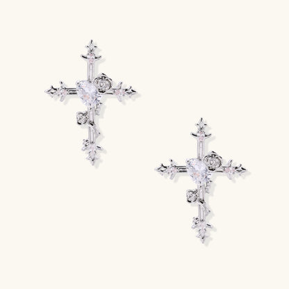 Ornate gold-plated cross earrings with zirconia stones and rose details on neutral background.